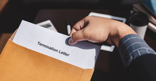Man holding a piece of paper that says "Termination Letter" on it